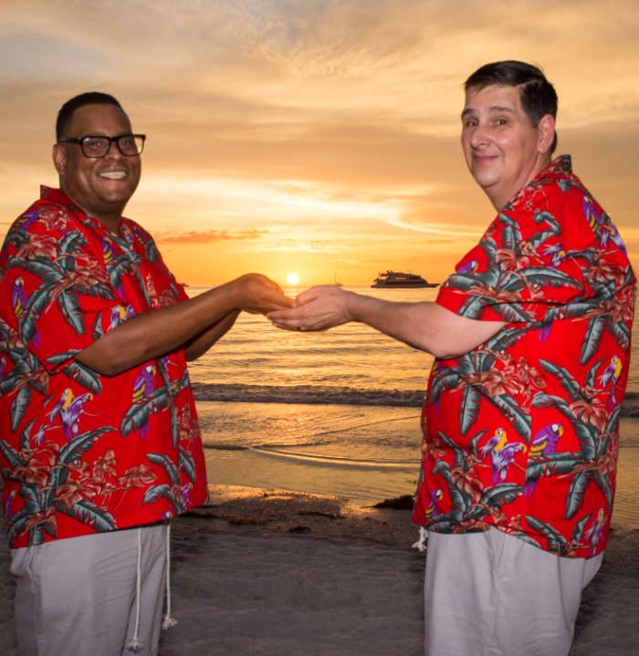 Same-sex couple at sunset on the beach, hands joined
